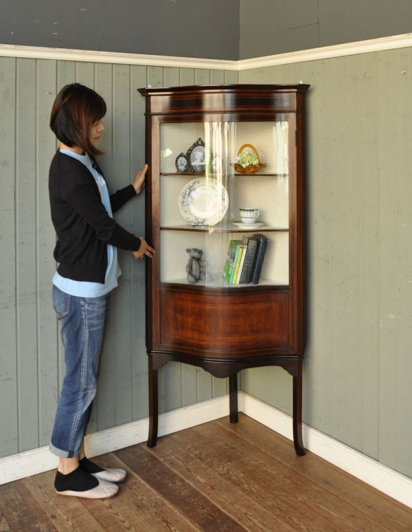 アンティークのキャビネット　アンティーク家具　角を有効に使うアンティーク家具、ガラス扉のコーナーキャビネット。お部屋の角にすっぽり収まる飾り棚！コーナーのオシャレにいかが？（モデルの身長は160cmです）【 全体 】幅75.5×奥行49.5×高さ160cm【 上から見たとき 】幅53.5×奥行53.5cm。(k-1135k-f)