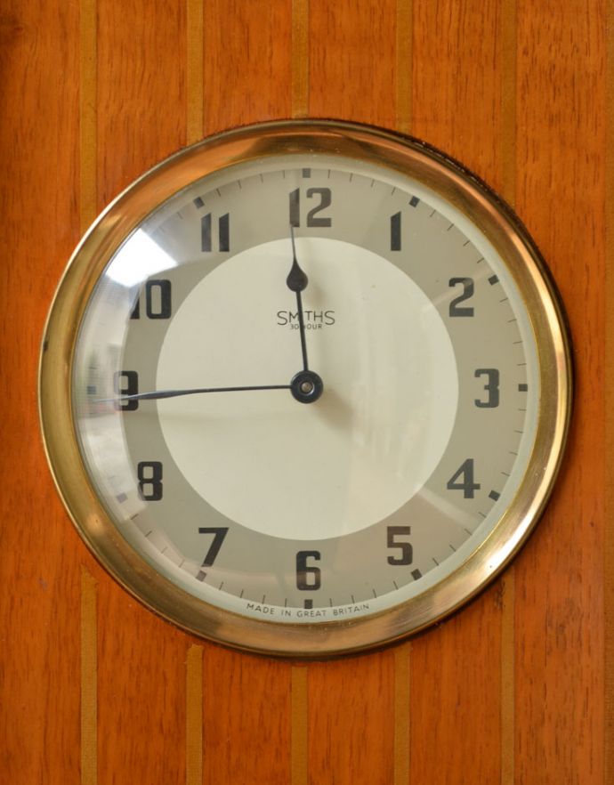 アンティークのキャビネット　アンティーク家具　ゴールドの装飾×時計が付いた英国アンティークのガラスキャビネット（飾り棚）。キャビネットの中央に時計がはめ込まれています。(k-1299-f)