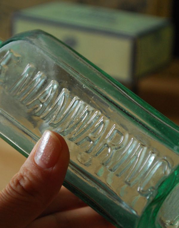 アンティーク雑貨　イギリス輸入のアンティーク雑貨、ふっくらとしたボディのガラスボトル。サイドにはエンボスの英字入りです。(k-1379-z)