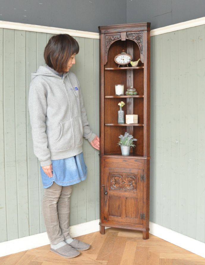 アンティークのキャビネット　アンティーク家具　お花の彫りが美しい英国アンティーク家具、オーク材のコーナーシェルフ。お部屋の角にすっぽり収まる飾り棚！コーナーのオシャレにいかが？（モデルの身長は163cmです）。(k-1403-f)