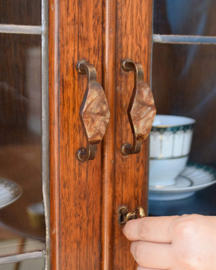 アンティークのキャビネット アンティーク家具 まるでステンドグラスの様なガラス扉が美しい、和室にも似合うアンティークの本棚。ちょっとめずらしいデザインの取っ手重厚感のあるハンドルタイプの取っ手の下にはカギ。(k-1466-f)