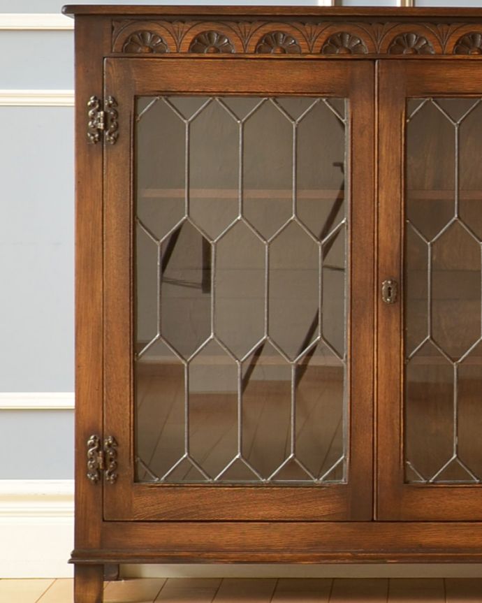 アンティークのキャビネット アンティーク家具 飾り棚にもなるアンティークの英国家具、お花の彫りが沢山付いたオーク材ブックケース(本棚)。アンティークのガラスがキレイにはめ込んであります。(k-1530-f)