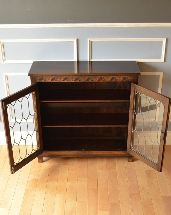 アンティークのキャビネット アンティーク家具 飾り棚にもなるアンティークの英国家具、お花の彫りが沢山付いたオーク材ブックケース(本棚)。内側も茶色なので落ち着きがあってかっこいいです。(k-1530-f)