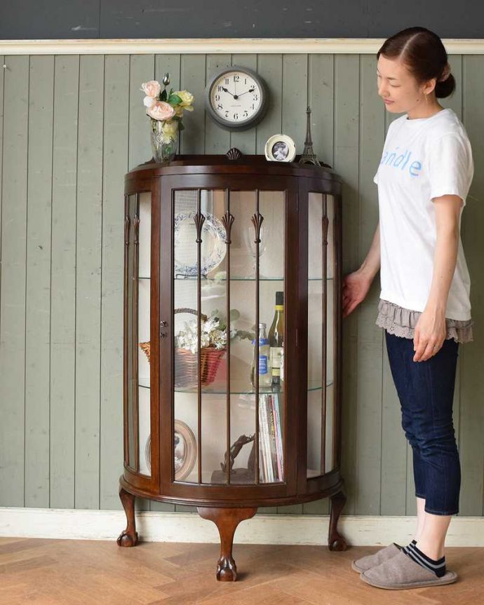 アンティークのキャビネット アンティーク家具 ウォルナット材を使ったイギリス家具、上品なアンティークのガラスキャビネット。180度どの角度からも中が見えるハーフムーンのキャビネット(モデルの身長はcmです)。(q-1103-f)