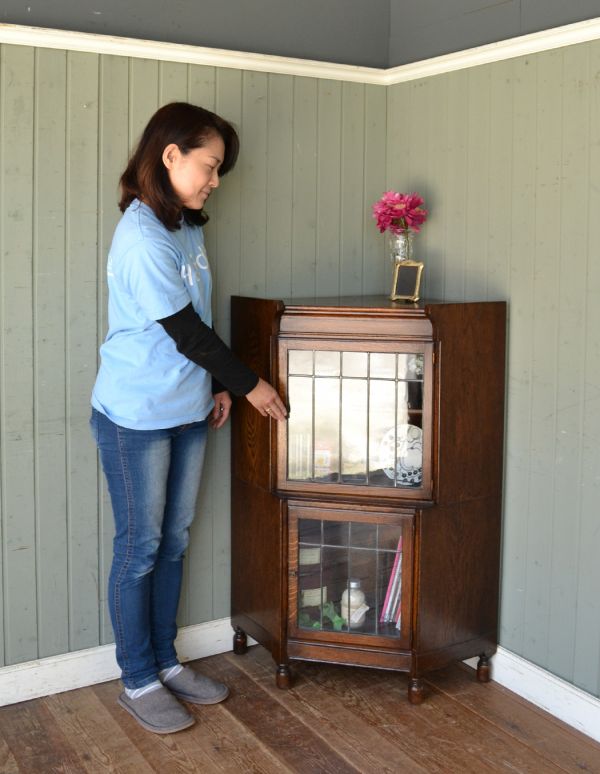 アンティーク家具　お部屋の角に置くアンティーク家具、コーナーガラスキャビネット。お部屋の角にすっぽり収まる飾り棚！コーナーのオシャレにいかが？（モデルの身長は158cmです）【 全体 】幅77×奥行56×高さ106cm。(q-424-f)