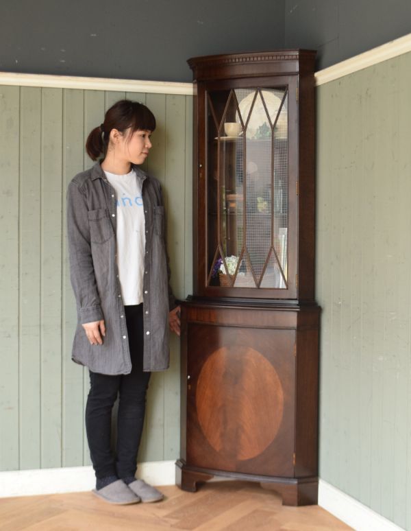 ガラスキャビネット　アンティーク家具　英国のアンティーク家具、マホガニー材を使った木製のコーナーキャビネット（食器棚）。お部屋の角にすっぽり収まる飾り棚！コーナーのオシャレにいかが？（モデルの身長は158cmです）。(q-567-f)