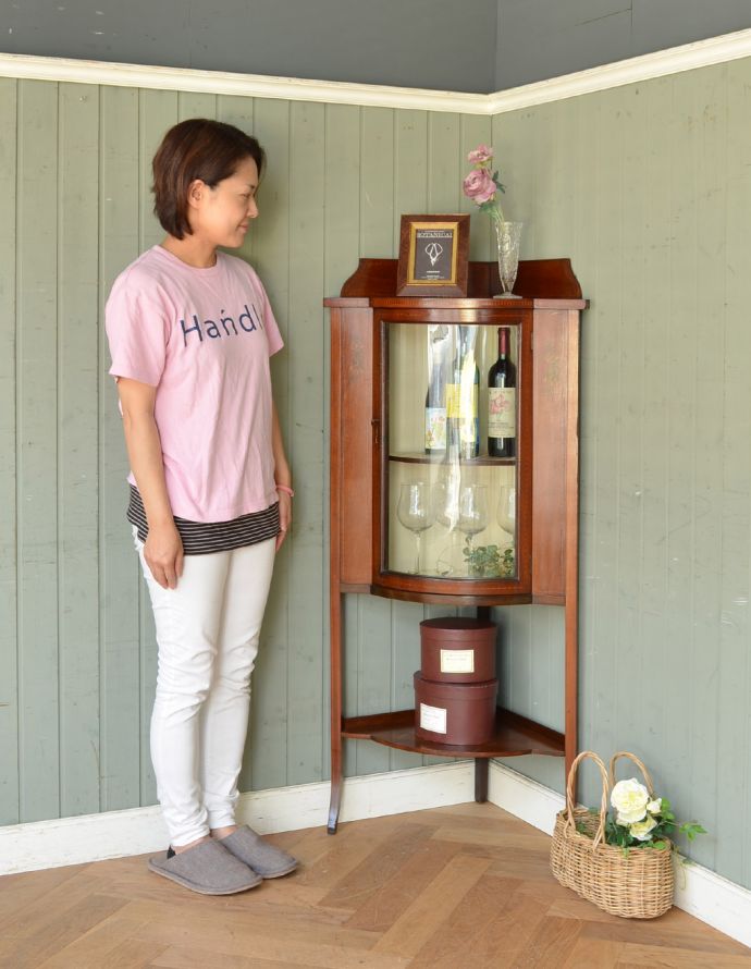 アンティークのキャビネット　アンティーク家具　角を有効に使うアンティーク家具、ガラスの曲線が美しいマホガニー材のコーナーキャビネット。お部屋の角にすっぽり収まる飾り棚！コーナーのオシャレにいかが？（モデルの身長は158cmです）【 全体 】幅60×奥行41×高さ131cm【壁についている面の寸法】39cm×2。(q-716-f)