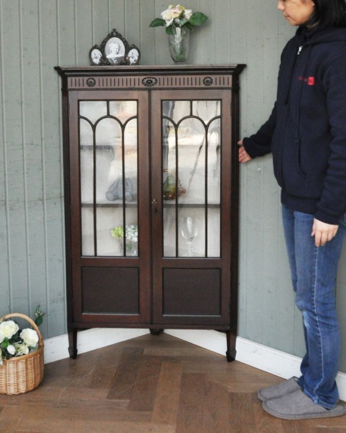 アンティークのキャビネット アンティーク家具 お花の彫刻が可愛いアンティークのコーナーガラスキャビネット(飾り棚) 。お部屋の角にすっぽり収まる飾り棚!コーナーのオシャレにいかが?(モデルの身長は159cmです)。(q-929-f)