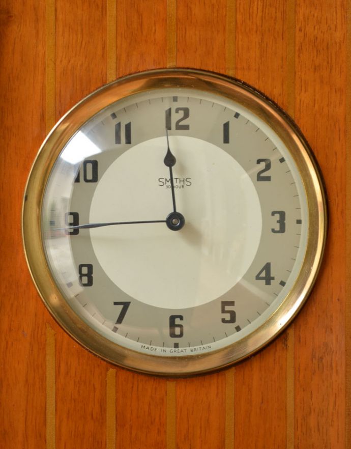 アンティークのキャビネット　アンティーク家具　ゴールドの装飾×時計が付いた英国アンティークのガラスキャビネット（飾り棚）。キャビネットの中央に時計がはめ込まれています。(k-1299-f)