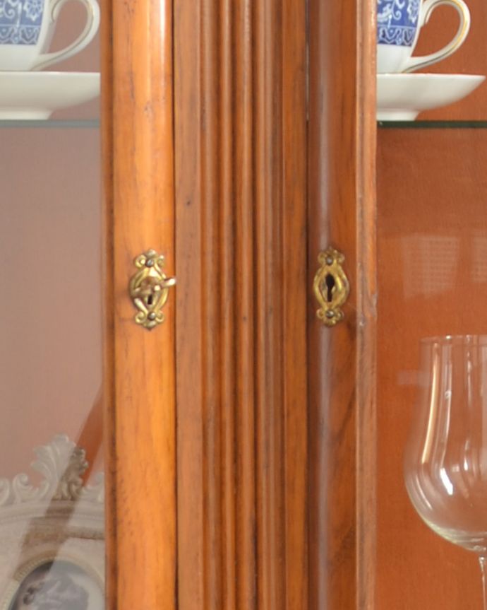 アンティークのキャビネット　アンティーク家具　イギリスのキレイなアンティーク家具、お花の彫りが刻まれた明るい色のガラスキャビネット。アンティークらしい凝った鍵穴。(k-1502-f)