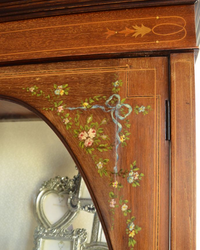 アンティークのキャビネット　アンティーク家具　リボンやお花がデザインされたアンティークの英国家具、ガラスキャビネット（飾り棚。ブルーのリボンと、華やかなお花の模様が施されています。(k-1560-f)
