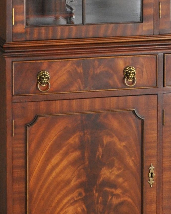アンティークのキャビネット　アンティーク家具　木目が華やかなマホガニー材のアンティーク家具、英国のガラスキャビネット（カップボード）。引き出しの取っ手は英国らしいライオンモチーフの素敵なデザインです。(k-1671-f)