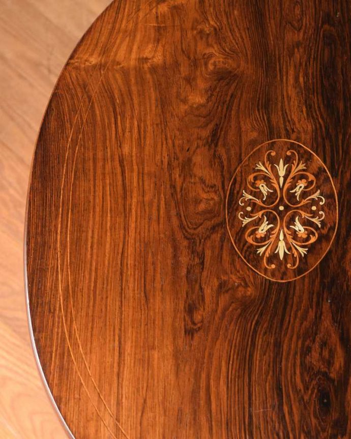 アンティークのテーブル　アンティーク家具　象嵌で模様が美しい棚付きのアンティークオケージョナルテーブル。天板を近づいてみると…アンティークだから手に入れることが出来る天板に使われている銘木の美しさにうっとりです。(k-2189-f)