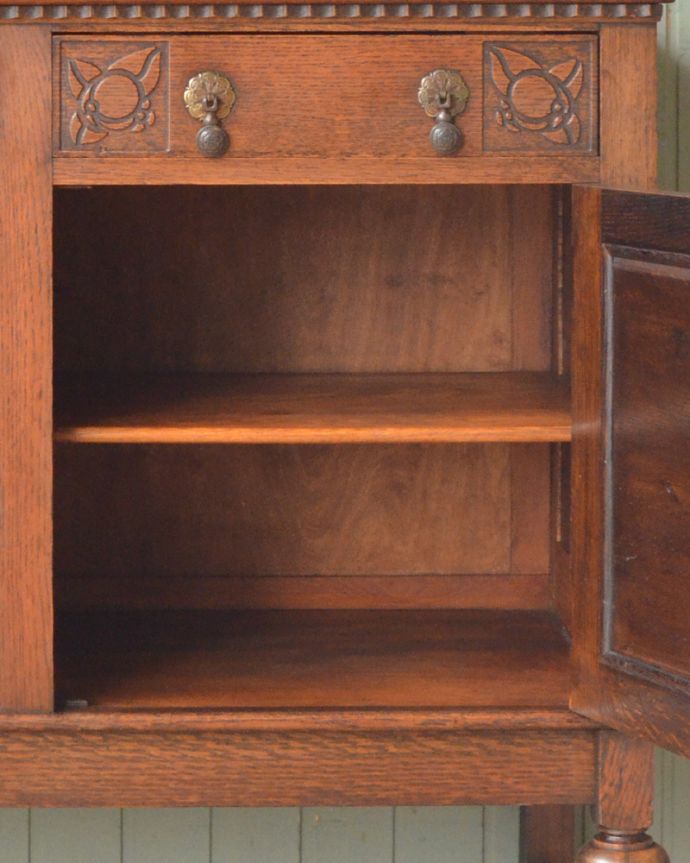 サイドボード　アンティーク家具　絵柄を刻んだサイドボード、英国のアンティーク家具。棚板は、左右共に１枚づつ付いています。(m-582-f)