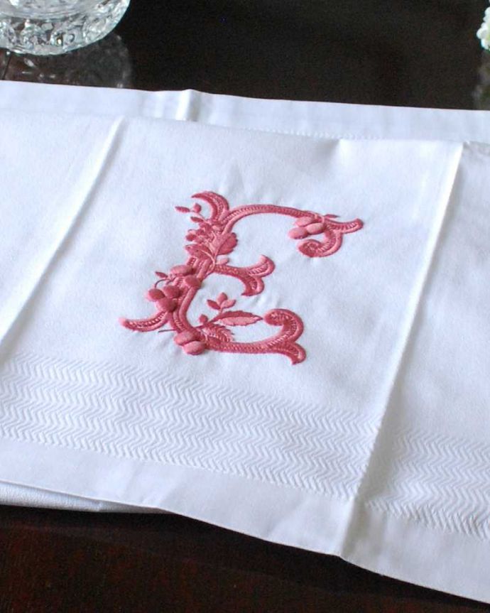 ファブリック（布）雑貨　インテリア雑貨　フランスのホームリネンの雰囲気が楽しめるモノグラムが入ったバスタオル「E」Red。上品なモノグラムのデザインジャガード織りのテキスタイルにイニシャルをオシャレに図案化されたモノグラムが上品に刺繍されています。(n9-046)
