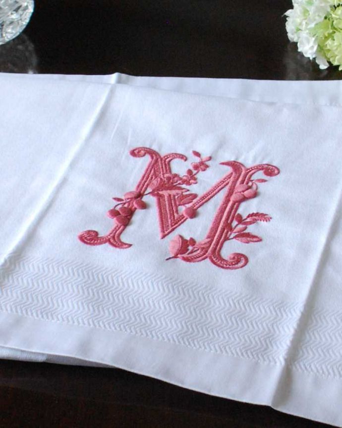ファブリック（布）雑貨　インテリア雑貨　フランスのホームリネンの雰囲気が楽しめるモノグラムが入ったバスタオル「M」Red。上品なモノグラムのデザインジャガード織りのテキスタイルにイニシャルをオシャレに図案化されたモノグラムが上品に刺繍されています。(n9-048)