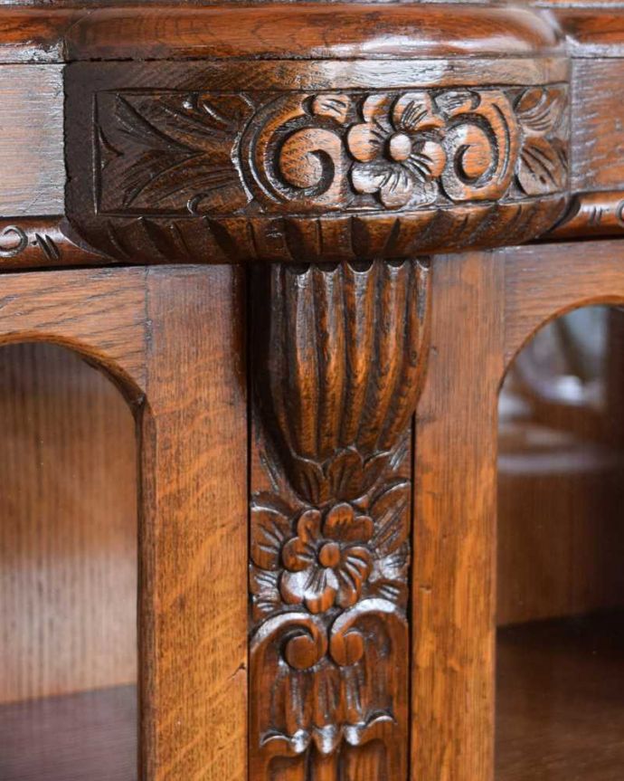 アンティークのキャビネット　アンティーク家具　イギリスアンティークの収納家具、お花の彫刻入りのブックケース（キャビネット）。いろんな場所にこだわり彫のデザインもいろいろです。(q-1701-f)