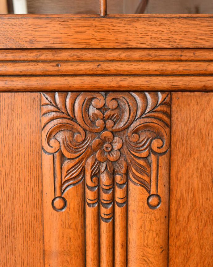 アンティークのキャビネット　アンティーク家具　イギリスアンティークの収納家具、お花の彫刻入りのブックケース（キャビネット）。いろんな場所にこだわり彫のデザインもいろいろです。(q-2044-f)