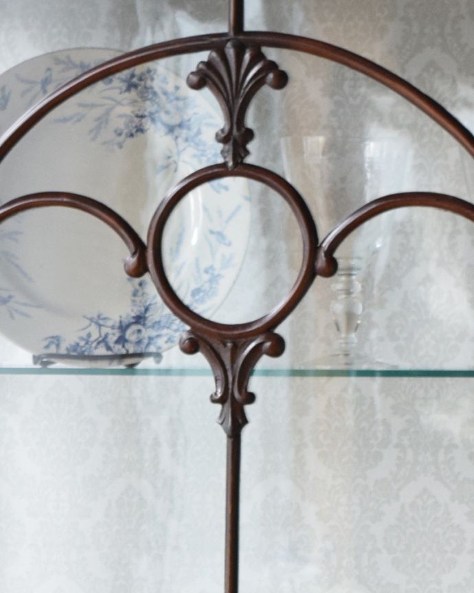 アンティークのキャビネット　アンティーク家具　英国輸入のアンティーク家具、繊細な木製の飾りが美しいマホガニー材のガラスキャビネット。お洒落なリングモチーフの装飾です。(q-961-f)