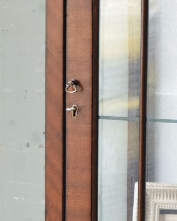 アンティークのキャビネット　アンティーク家具　英国輸入のアンティーク家具、繊細な木製の飾りが美しいマホガニー材のガラスキャビネット。小さな取っ手と鍵穴が付いています。(q-961-f)