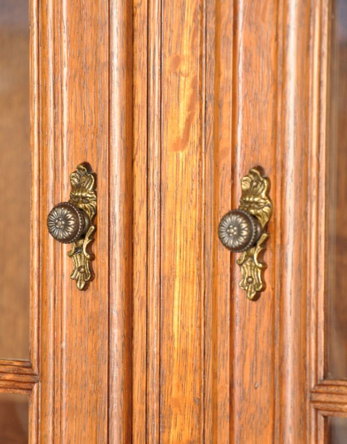 アンティークのキャビネット　アンティーク家具　フランスならではのゴージャスな装飾を施したアンティークガラスキャビネット。アンティークらしい繊細なデザインの取っ手がちょこんと付いています。(j-1621-f)