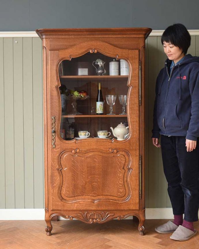 アンティークのキャビネット アンティーク家具 リビングで使えるフランスのアンティーク家具、一枚扉のガラスキャビネット。フランスらしい優雅さと風格が自慢ドッシリと重厚感ある佇まいとフランスらしい優雅な彫の両方を贅沢にも兼ね備えたガラスのキャビネット。(j-2381-f)