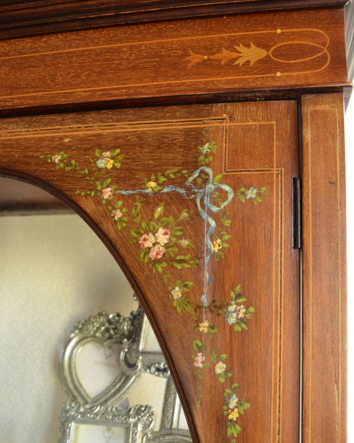 アンティークのキャビネット アンティーク家具 リボンやお花がデザインされたアンティークの英国家具、ガラスキャビネット(飾り棚。ブルーのリボンと、華やかなお花の模様が施されています。(k-1560-f)