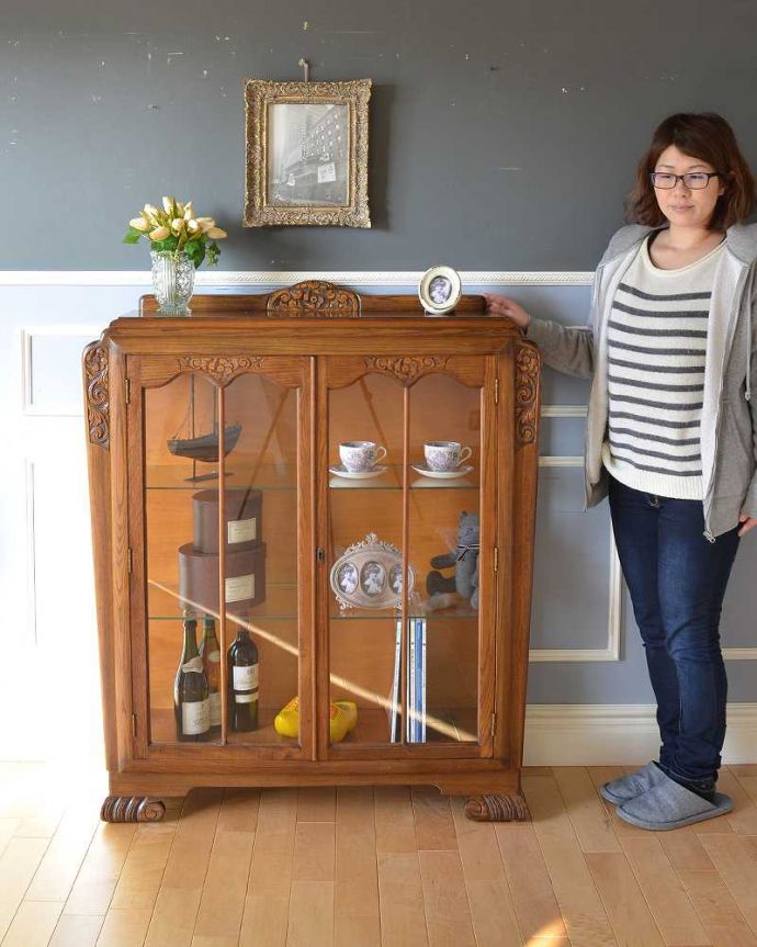 アンティークのキャビネット　アンティーク家具　お花の彫刻が華やかなアンティークキャビネット(ショーケース)。英国らしい堂々とした風格のあるガラスキャビネット重厚感ある佇まいで、落ち着いた雰囲気を演出してくれる英国のキャビネット。(k-1963-f)