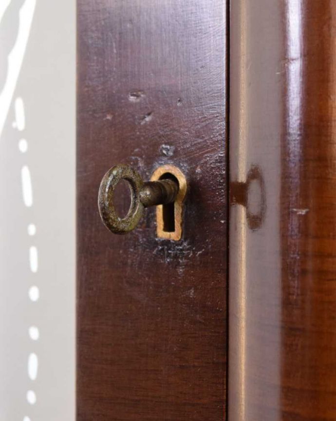 アンティークのキャビネット アンティーク家具 英国輸入のアンティーク家具、ガラスの装飾も美しいミラー付きガラスキャビネット 。開ける度にワクワクする取っ手鍵が取っ手になっているので、中を開ける度にまるで宝箱を開ける気分です。(k-2158-f)