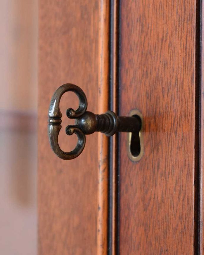 アンティークのキャビネット　アンティーク家具　木目が美しい英国のアンティーク家具、お部屋の角に置けるコーナーキャビネット。開ける度にワクワクアンティークらしい取っ手のデザイン。(k-2186-f)