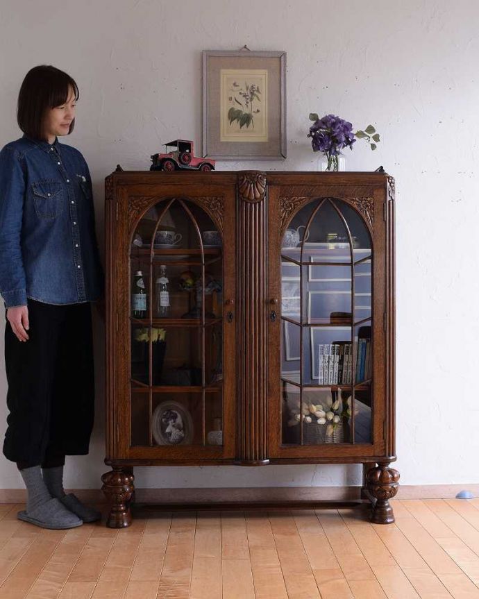 アンティークのキャビネット アンティーク家具 英国から到着したアンティーク家具、お花の彫りが美しい木製のブックケース(本棚) 。英国らしい堂々とした風格のあるガラスキャビネット重厚感ある佇まいで、落ち着いた雰囲気を演出してくれる英国のキャビネット。(k-2201-f)