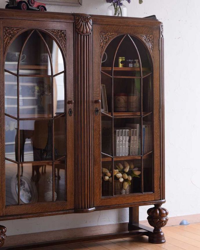 アンティークのキャビネット アンティーク家具 英国から到着したアンティーク家具、お花の彫りが美しい木製のブックケース(本棚) 。ガラス越しに中をのぞいてみると・・・アンティークのガラスを通して中に入っているものを見ると、なんだかちょっと高級に見えるんです。(k-2201-f)