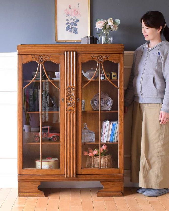 アンティークのキャビネット　アンティーク家具　イギリスアンティークの収納家具、お花の彫刻入りのブックケース（キャビネット）。英国らしい堂々とした風格のあるガラスキャビネット重厚感ある佇まいで、落ち着いた雰囲気を演出してくれる英国のキャビネット。(k-2319-f)