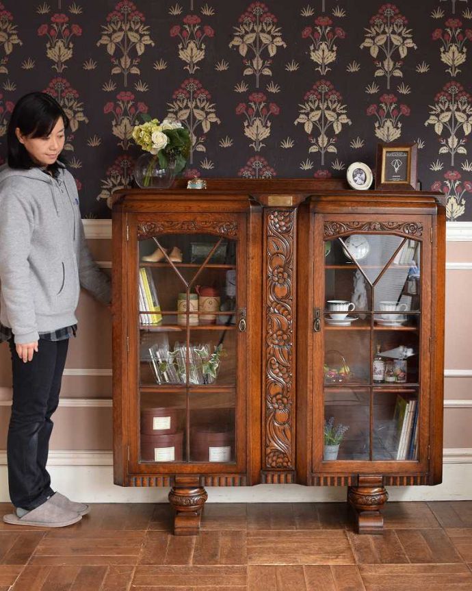 アンティークのキャビネット アンティーク家具 英国のアンティーク家具、お花の彫刻が華やかなブックケース。英国らしい堂々とした風格のあるキャビネット重厚感ある佇まいで、落ち着いた雰囲気を演出してくれる所が英国アンティークのよさ。(q-1353-f)