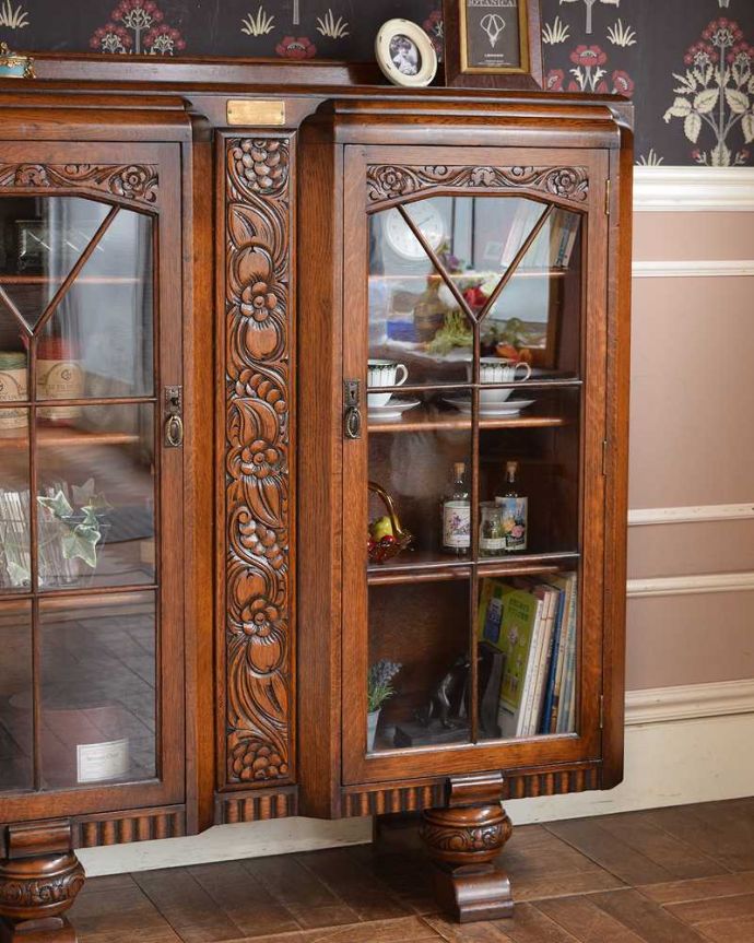 アンティークのキャビネット アンティーク家具 英国のアンティーク家具、お花の彫刻が華やかなブックケース。ガラス越しに中をのぞいてみると・・・アンティークのガラスを通して見ると、どんなものでも中に入れたものが、ちょっと高級に見えちゃうんです。(q-1353-f)