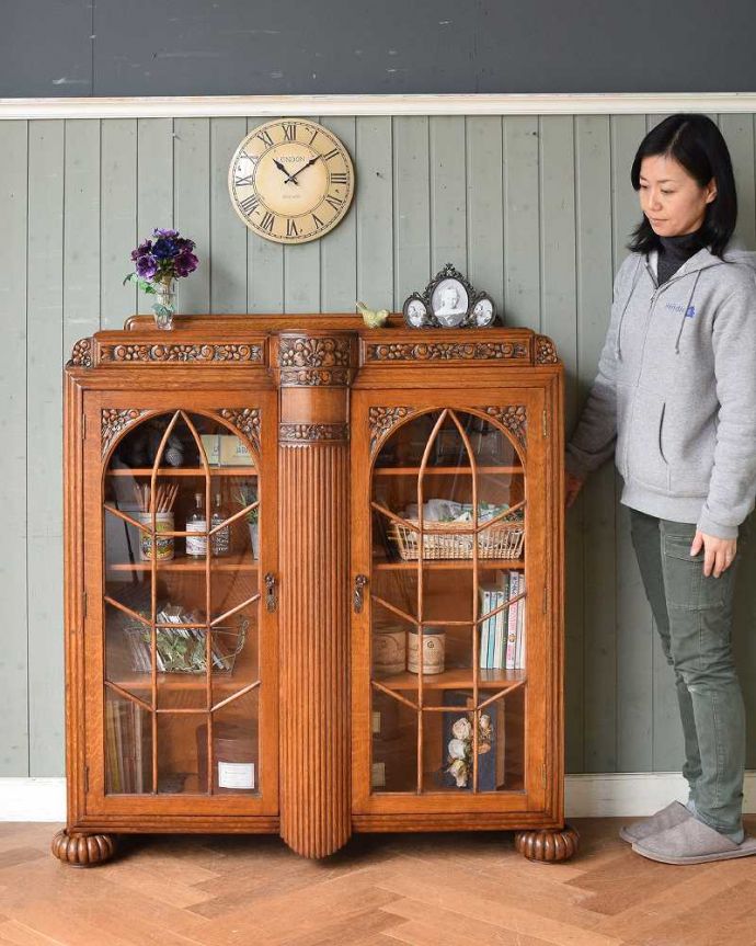 アンティークのキャビネット　アンティーク家具　華やかなアンティークの英国家具、お花の彫刻入りのブックケース（本棚） 。英国らしい堂々とした風格のあるガラスキャビネット重厚感ある佇まいで、落ち着いた雰囲気を演出してくれる英国のキャビネット。(q-1389-f)