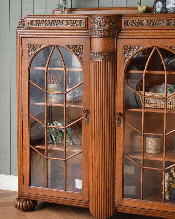 アンティークのキャビネット　アンティーク家具　華やかなアンティークの英国家具、お花の彫刻入りのブックケース（本棚） 。ガラス越しに中をのぞいてみると･･･アンティークのガラスを通して中に入っているものを見ると、なんだかちょっと高級に見えるんです。(q-1389-f)