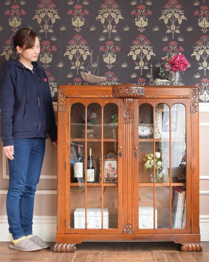 アンティークのキャビネット　アンティーク家具　英国輸入のアンティークの収納家具、お花の彫刻入りのブックケース（キャビネット）。英国らしい堂々とした風格のあるガラスキャビネット重厚感ある佇まいで、落ち着いた雰囲気を演出してくれる英国のキャビネット。(q-1413-f)