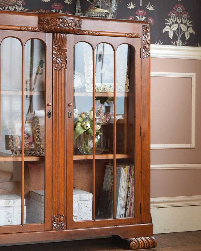 アンティークのキャビネット　アンティーク家具　英国輸入のアンティークの収納家具、お花の彫刻入りのブックケース（キャビネット）。ガラス越しに中をのぞいてみると･･･アンティークのガラスを通して中に入っているものを見ると、なんだかちょっと高級に見えるんです。(q-1413-f)