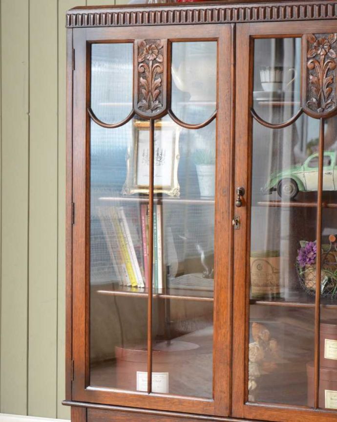 アンティークのキャビネット　アンティーク家具　イギリスから届いたアンティーク家具、お花の彫りが美しい木製のブックケース（本棚）。ガラス越しに中をのぞいてみると･･･アンティークのガラスを通して中に入っているものを見ると、なんだかちょっと高級に見えるんです。(q-1581-f)