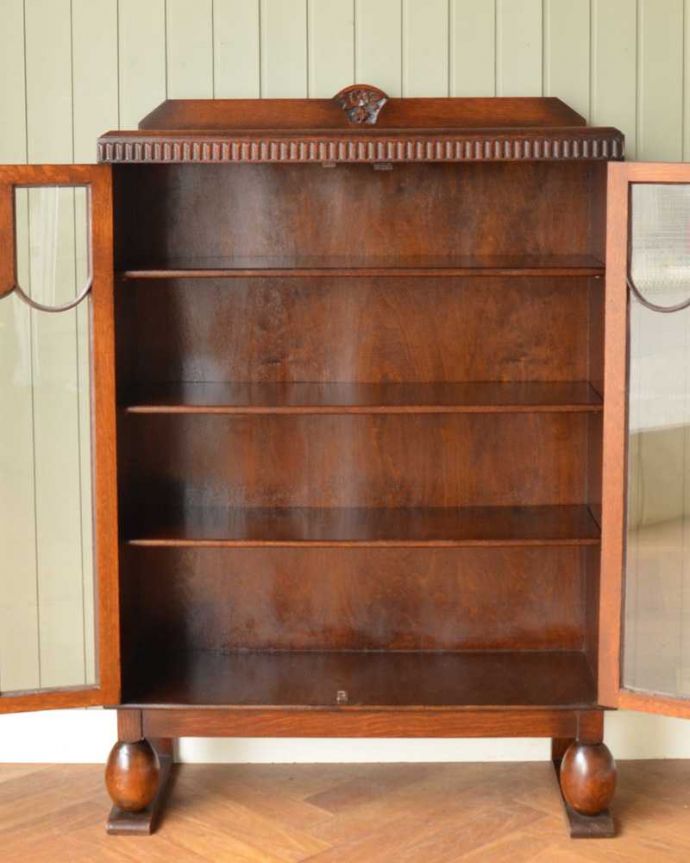 アンティークのキャビネット　アンティーク家具　イギリスから届いたアンティーク家具、お花の彫りが美しい木製のブックケース（本棚）。扉の中は、しっかりと収納できる棚板重いものもたっぷり収納できる木製の棚板タイプ。(q-1581-f)