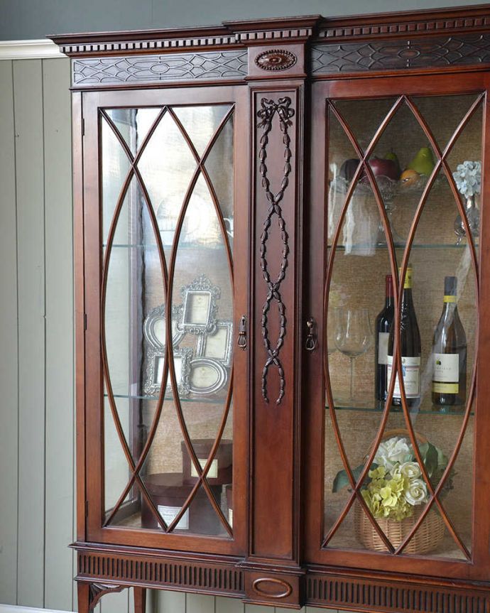 アンティークのキャビネット　アンティーク家具　アンティークの大きな英国家具、リボンの装飾が優雅なガラスキャビネット（ショーケース）。扉に描かれた模様の美しさアンティークのガラスを通して中に入っているものを見ると、なんだかちょっと高級に見えるんです。(q-1677-f)