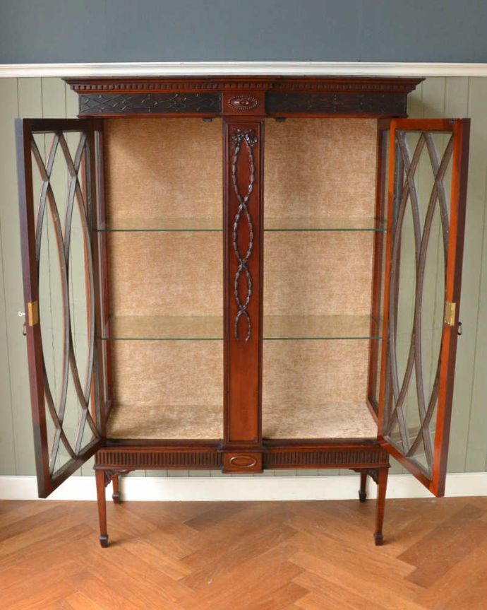 アンティークのキャビネット　アンティーク家具　アンティークの大きな英国家具、リボンの装飾が優雅なガラスキャビネット（ショーケース）。扉を開けて中を見てみましょう職人がキレイに修復して、背板も新しい生地に張替えました。(q-1677-f)