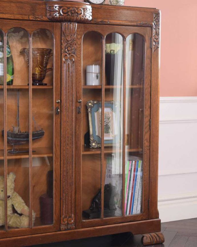 アンティークのキャビネット　アンティーク家具　花の彫りが華やかなアンティークの英国家具、鍵付きのブックケース（本棚）。ガラス越しに中をのぞいてみると･･･アンティークのガラスを通して中に入っているものを見ると、なんだかちょっと高級に見えるんです。(q-1685-f)