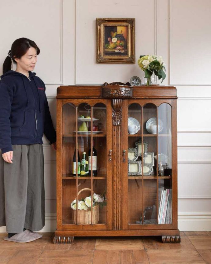 アンティークのキャビネット　アンティーク家具　イギリスアンティークの収納家具、お花の彫刻入りのブックケース（キャビネット）。英国らしい堂々とした風格のあるガラスキャビネット重厚感ある佇まいで、落ち着いた雰囲気を演出してくれる英国のキャビネット。(q-1701-f)