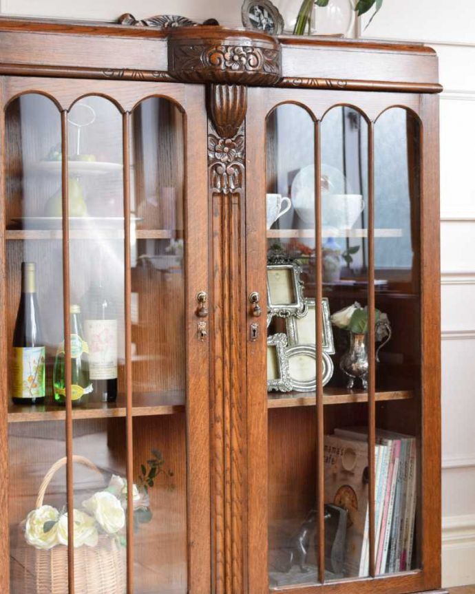 アンティークのキャビネット　アンティーク家具　イギリスアンティークの収納家具、お花の彫刻入りのブックケース（キャビネット）。ガラス越しに中をのぞいてみると･･･アンティークのガラスを通して中に入っているものを見ると、なんだかちょっと高級に見えるんです。(q-1701-f)