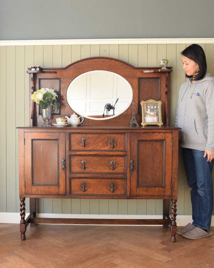 アンティークのキャビネット　アンティーク家具　オーバルミラー付きの英国アンティーク家具、オーク材のミラーバックサイドボード。鏡がキラっと輝くサイドボード光を取り込んでキラキラ輝くミラーは、まだ電気が発達していなかった時代に太陽や蝋燭の灯りを反射させて部屋を明るくするために付けられたもの。(q-1735-f)