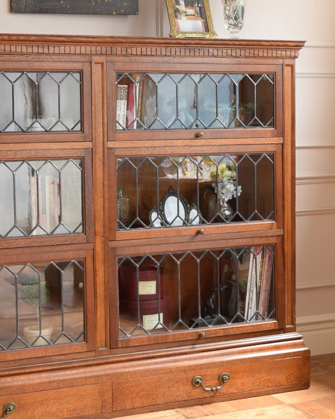 アンティーク家具 美しい格子デザインのガラス扉がキラキラ輝くアンティークの英国家具、フラップ扉のブックケース。まずはステンドグラスを楽しみましょう現代のように機械が発達していない時代に作られたステンドグラス。(q-1852-f)