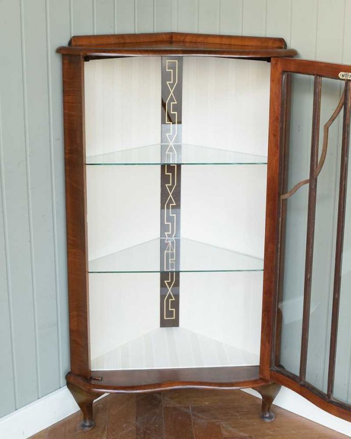 アンティークのキャビネット アンティーク家具 英国輸入のアンティーク家具、木の装飾が上品なコーナーガラスキャビネット。扉を開けて中を見てみると…職人がキレイに修復して、背板も新しい生地に張替えました。(q-1874-f)