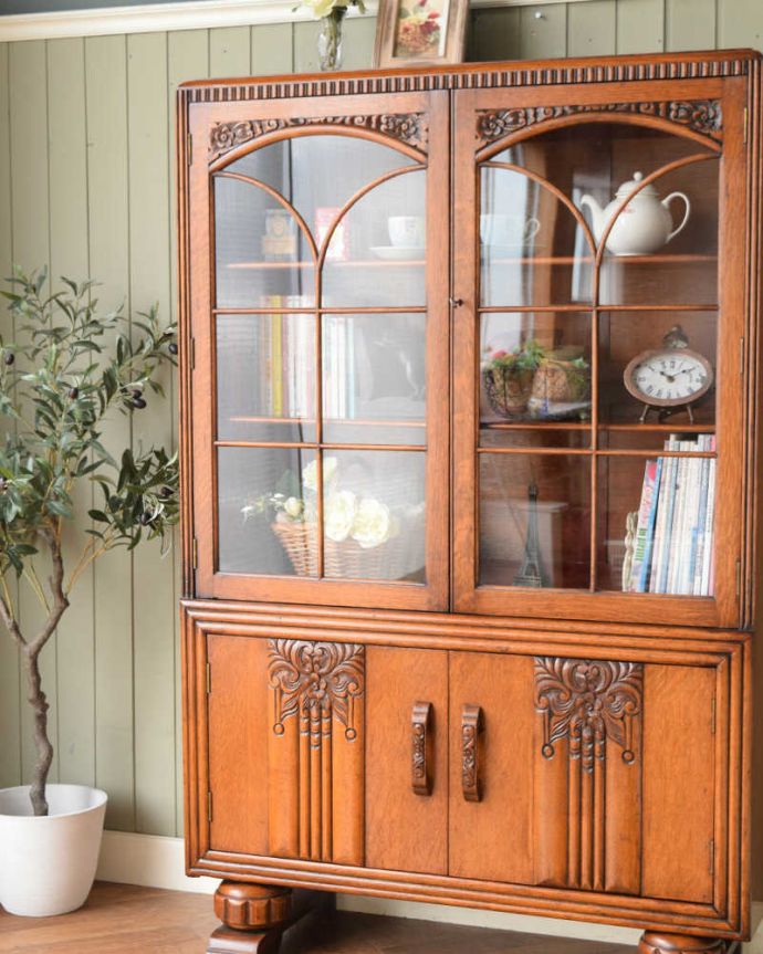 アンティークのキャビネット　アンティーク家具　イギリスアンティークの収納家具、お花の彫刻入りのブックケース（キャビネット）。ガラス越しに中をのぞいてみると･･･アンティークのガラスを通して中に入っているものを見ると、なんだかちょっと高級に見えるんです。(q-2044-f)